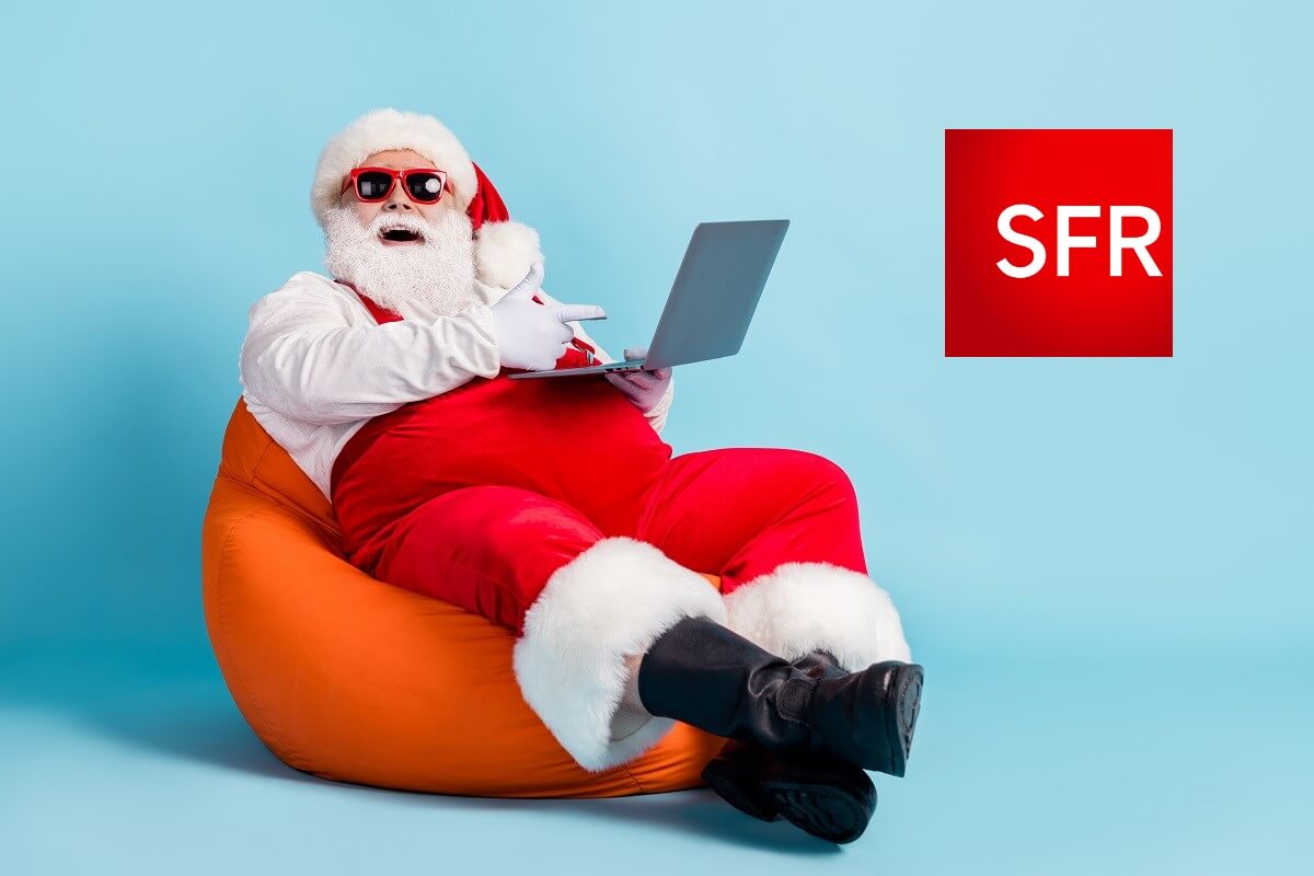 Père Noël sur pouf orange avec PC portable et logo de SFR, car SFR propose la fibre pas chère et sans frais de mise en service pour les Fêtes