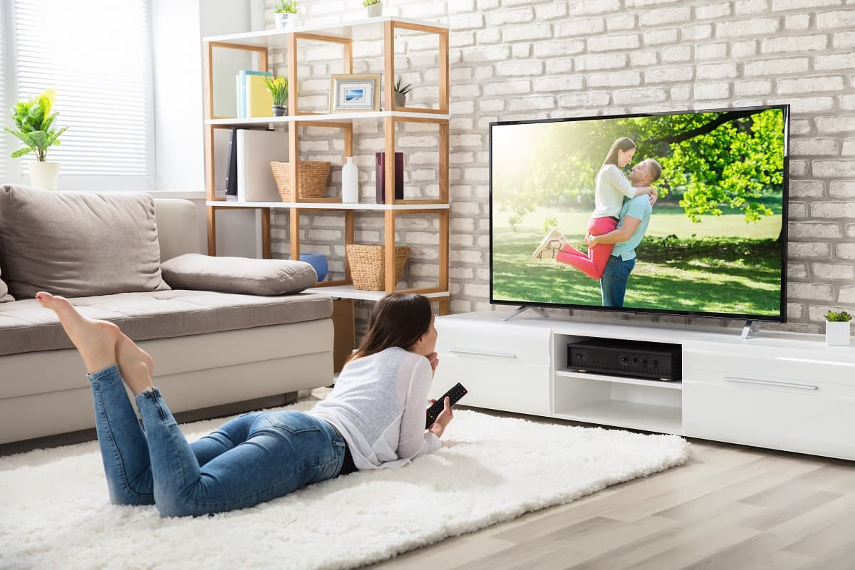 Femme regard smart TV dans salon, sans décodeur, mais super connexion de "Pure Fibre", nouvelle Box de B&You