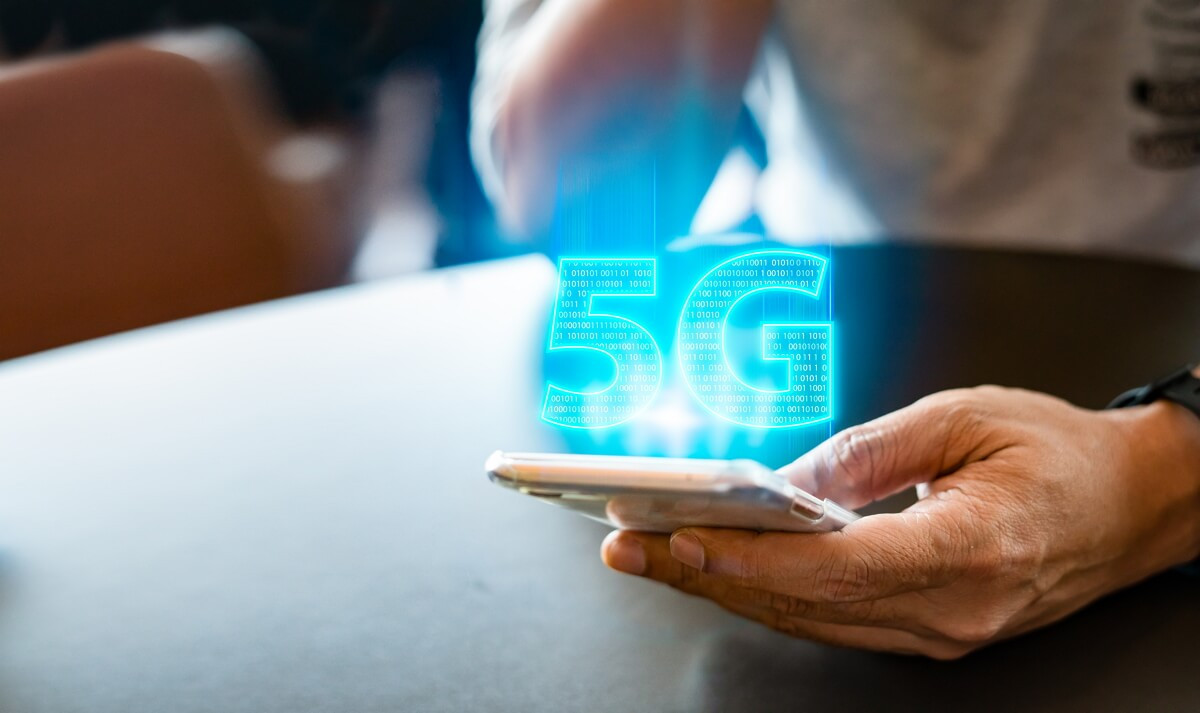 Logo 5G bleu sort du smartphone, car elle est enfin disponible chez Auchan Telecom